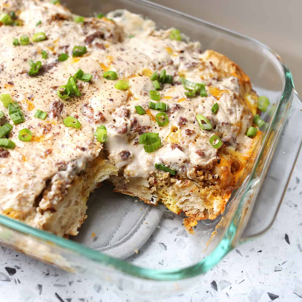 biscuits and gravy casserole in glass pan with one piece missing