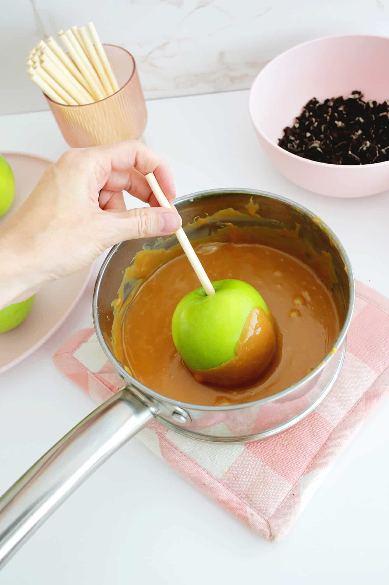 Dipping an apple on a stick into caramel
